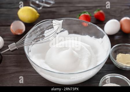 Nahaufnahme eines Schneebesen und geschlagenem Eiweiß zu steifen Gipfeln, ein Schritt bei der Zubereitung von Frühstücksteig oder zarten Pfannkuchen. Weißer geschlagener Ei-Schaum Stockfoto