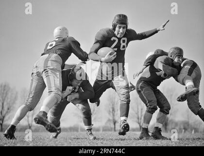 1940S FÜNF FÜNF FUSSBALLSPIELER AUF DEM SPIELFELD EIN SPIELER, DER DEN BALL TRÄGT UND ZWISCHEN DEN TACKLERS-SPIELEN FREI UND FREI DURCHKOMMT BLOCKIERT - F2486 HAR001 HARS GET PLAYERS B&W ZIELE ABENTEUER SCHUTZ STRATEGIE UNIVERSITÄTEN UND SPANNUNG LOW-ANGLE-ERHOLUNG RICHTUNG A BEI GELEGENHEIT HABEN DIE ZWISCHEN DEN FREIEN UNIFORMEN BLOCKIERTE KONZEPTIONELLE ATHLETEN ESCAPE SUPPORT COLLEGES GEGEN KLARE COLLEGIATE KOOPERATION FUSSBÄLLE TEAMS JUNG ERWACHSENER MANN AMERICAN FOOTBALL SCHWARZ-WEISS HAR001 ALTMODISCH Stockfoto