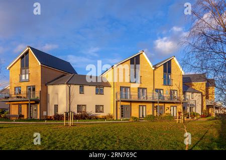 Ein neues Wohnhaus an einem sehr frühen Dezembermorgen. Die Sonne dämmert und erleuchtet das Anwesen und jagt die Nachtwolken vom blauen Himmel weg. Stockfoto