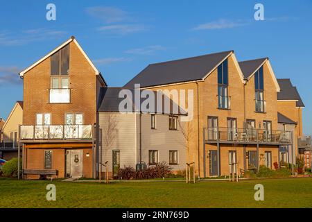 Ein neues Wohnhaus an einem sehr frühen Dezembermorgen. Die Sonne dämmert und erleuchtet das Anwesen und jagt die Nachtwolken vom blauen Himmel weg. Stockfoto