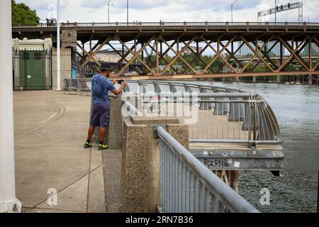 Man stellte eine Kamera auf, um ein Foto von der N Steel Bridge über dem Willamette River im Zentrum von Portland, Oregon, zu machen Stockfoto