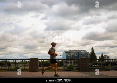 Ein Mann, der am Willamette River im Tom McCall Waterfront Park in der Innenstadt von Portland, Oregon, entlang läuft Stockfoto