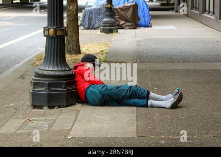 Obdachloser, der Drogen nimmt, ruht auf dem Bürgersteig im Zentrum von Portland Oregon Stockfoto