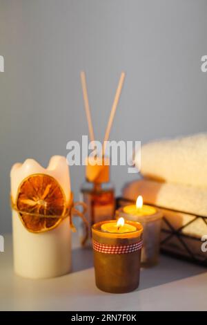Es gibt beleuchtete Aromakerzen auf dem Tisch, Handtücher für Eingriffe liegen. Nahaufnahme. Spa-Behandlungsraum. Vertikaler Rahmen Stockfoto