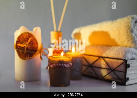 Es gibt beleuchtete Aromakerzen auf dem Tisch, Handtücher für Eingriffe liegen. Nahaufnahme. Spa-Behandlungsraum. Stockfoto