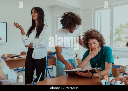 Eine vielfältige Gruppe von Schülern versammelt sich in einem modernen Klassenzimmer und führt leidenschaftlich lebhafte Diskussionen über verschiedene Projekte Stockfoto