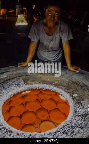 (150923) -- TURPAN, 23. September 2015 -- Foto aufgenommen am 16. September 2015 zeigt Abduweli Rozi, der auf das Backen von nang, einer Art knusprigem Brot, in seiner Werkstatt in Turpan, Nordwestchinas autonomer Region Xinjiang Uygur, wartet. Fast jeden frühen Morgen wachen der 45-jährige Abduweli Rozi und seine Frau vor 3 Uhr auf und beginnen ihre Arbeit. In den nächsten 10 Stunden machten sie 300 nang und verteilten sie an Verkäufer in der Stadt. Dies ist nur ein Teil der Geschichte, die jeden Tag in einer kooperativen Gruppe von nang-Machern in Turpan stattfand. Neben Abduweli Rozis Famliy arbeiten 17 Familien in einem jahr zusammen Stockfoto