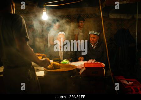 (150930) -- KASHGAR, 30. September 2015 -- Bewohner essen lokale Snacks auf einer Nachtmesse in der Altstadt von Kashgar, Nordwestchinas Autonome Region Xinjiang Uygur, 23. September 2015. Kashgar, die westlichste Stadt Chinas, war jahrhundertelang das Zentrum der uygurischen Zivilisation, ein Ort, an dem Menschen zusammenkamen, um islamisches Lernen zu handeln und zu verbreiten, auf den Karawanenrouten von Europa und Persien nach China. ) (lfj) CHINA-XINJIANG-KASHGAR-OLD TOWN (CN) ZhangxCheng PUBLICATIONxNOTxINxCHN Kashgar Sept 30 2015 Einwohner essen lokale Snacks AUF einer Nachtmesse in der Altstadt von Kashgar Nordwestchina S Xinjiang Uy Stockfoto