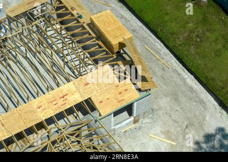 Bauarbeiter, die an der Dachkonstruktion eines unfertigen Wohnhauses mit Holzrahmenstruktur im Vorstadtgebiet von Florida arbeiten. Wohnungsbau Stockfoto