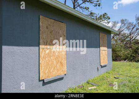 Verkleidete Fenster mit Sperrholzläden zum Schutz von Wohnhäusern vor Hurrikanen. Schutzmaßnahmen vor Naturkatastrophen in Florida Stockfoto