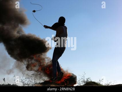 (151030) -- GAZA, 30. Oktober 2015 -- Ein palästinensischer Demonstrant verwendet eine Schleuder, um Steine auf israelische Truppen zu werfen, während Zusammenstöße in der Nähe der Grenze zwischen Israel und dem zentralen Gazastreifen, 30. Oktober 2015. Drei Palästinenser wurden getötet und mehr als 75 andere verwundet an einem Tag voller brennender Spannungen und gewalttätiger Konfrontationen mit israelischen Sicherheitskräften in den palästinensischen Gebieten, sagten Beamte des gesundheitsministeriums am Freitag. MIDEAST-GAZA-ZUSAMMENSTÖSSE JasserxQudih PUBLICATIONxNOTxINxCHN Gaza OCT 30 2015 ein PALÄSTINENSISCHER Demonstrant verwendet eine Schleuder, um Steine auf israelische Truppen während der Zusammenstöße in der Nähe der zu werfen Stockfoto