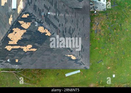 Das Dach ist kaputt und muss repariert werden. Durch Wind beschädigtes Hausdach mit fehlenden Asphaltschindeln nach Hurrikan Ian in Florida Stockfoto