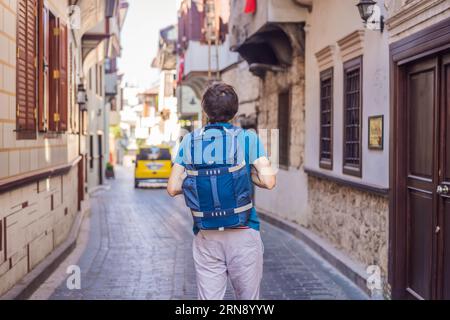 Glücklicher Mann Tourist auf dem Hintergrund der alten Straße von Antalya. Männliche Touristen entdecken interessante Orte und beliebte Attraktionen und Spaziergänge in der Stockfoto