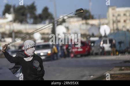 (151120) -- RAMALLAH, 20. November 2015 -- Ein palästinensischer Demonstrant wirft mit einer Schleuder Steine auf israelische Soldaten während der Auseinandersetzungen mit israelischen Truppen und palästinensischen Demonstranten in der Nähe der jüdischen Siedlung Bet El, in der Nähe der Westbank-Stadt Ramallah, 20. November 2015. Eine Welle der Spannungen zwischen Palästinensern und Israelis, die Anfang Oktober begann, hat sich zu gewaltsamen Konfrontationen in den palästinensischen Gebieten verschlechtert. Nach Angaben des palästinensischen gesundheitsministeriums wurden 89 Palästinenser getötet und mehr als 3.000 verwundet, während israelische Medien sagen, dass 14 Israelis in Sta getötet wurden Stockfoto