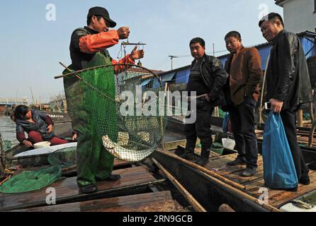 HUZHOU, Foto aufgenommen am 30. November 2015 zeigt den Fischer Song Boliang (2. L) und seine Frau Meng Xizhen (1. L), der Fisch auf ihrem Fischerboot verkauft, nachdem er vom südlichen Taihu-See in Huzhou, der ostchinesischen Provinz Zhejiang, zurückgekehrt ist. Der 46-jährige Song Boliang lebte im Dorf Huanlou im Bezirk Wuxing in Huzhou und wurde auf einem Fischerboot geboren. Song und seine Frau, die letzte Generation von Fischern am südlichen Taihu-See, werden bald ihr Zuhause von Fischerboot zu Haus am Ufer verlegen. Sie gehören zu den 106 Fischerfamilien des Dorfes Huanlou, die von der lokalen Regierung geplant sind, sich unter Verbot niederzulassen Stockfoto