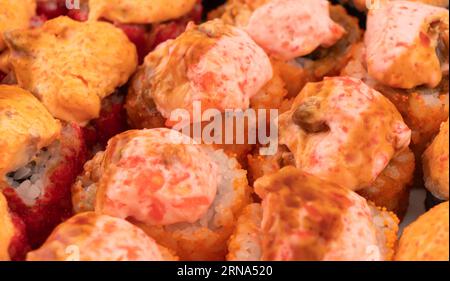 Set von gebackenen Sushi-Rollen isoliert auf schwarzem Hintergrund. Gebackene Sushi-Rolle isoliert. Traditionelles japanisches Essen mit Maki leckeren Sushi-Stücken Stockfoto