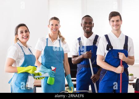 Portrait von Happy Diverse Hausmeister im Büro mit der Reinigung der Geräte Stockfoto