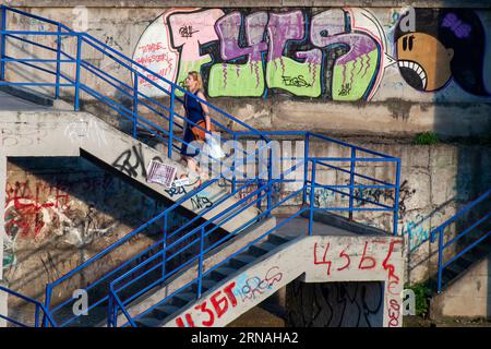 Eine Frau, die die Treppen hinaufsteigt, bedeckt mit bunten Graffiti-Kunstwerken Stockfoto