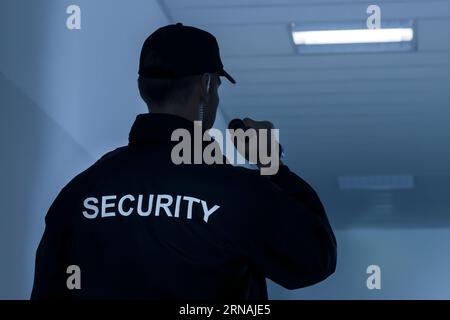 Ansicht der Rückseite des Security Guard mit Taschenlampe in Gebäude Korridor Stockfoto