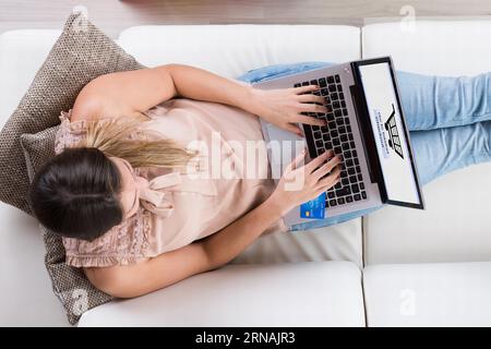 Junge Frau sitzt auf einem Sofa mit Laptop Online Einkaufen Stockfoto