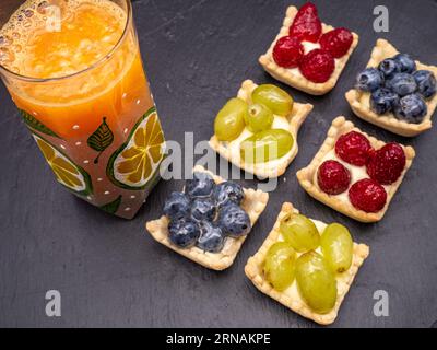 Nachtisch aus frischem Obst und Beerentorte auf Schiefer Stockfoto