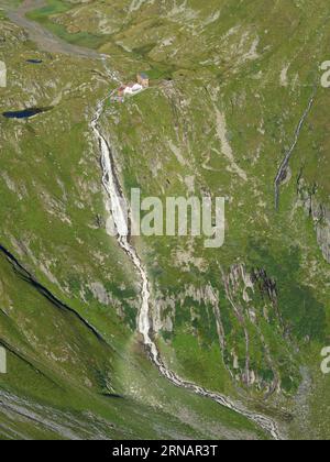 LUFTAUFNAHME. Die neue Regensburger Hütte, eine Berghütte mit Blick auf den Falbesoner Wasserfall. Neustift im Stubaital, Tirol, Österreich. Stockfoto