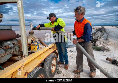 Salzbergleute, die Wasser zwischen Verdunstungsteichen bei der WA Salt Supply Company in Lake Deborah, Western Australia, pumpen Stockfoto