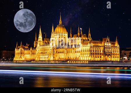 Ein Vollmond am Nachthimmel über dem ungarischen Parlamentsgebäude, beleuchtet in der Dunkelheit Stockfoto