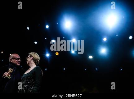 Der italienische Regisseur Gianfranco Rosi (L) hält die Trophäe des Goldenen Bären für den besten Film, während er mit Jurypräsident Meryl Streep während der Preisverleihung des 66. Berlinale International Film Festival in Berlin, Deutschland, am 20. Februar 2016 spricht. Der italienische Dokumentarfilm Fire at Sea gewann am Samstag beim 66. Internationalen Filmfestival Berlin den Goldenen Bären, den besten Jury-Preis für den besten Film. DEUTSCHLAND-BERLIN-BERLINALE INTERNATIONAL FILM FESTIVAL-AWARDS ZEREMONIE-GOLD BÄR-GIANFRANCO ROSI ZhangxFan PUBLICATIONxNOTxINxCHN italienischer Regisseur Gian Franco Rosi l hält die Trophäe des Goldenen Stockfoto