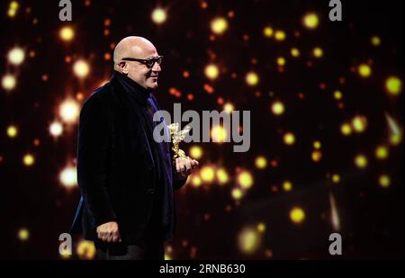 Der italienische Regisseur Gianfranco Rosi hält die Trophäe des Goldenen Bären als bester Film für den Film Fire at Sea während der Preisverleihung des 66. Berlinale International Film Festival in Berlin, 20. Februar 2016. Der italienische Dokumentarfilm Fire at Sea gewann am Samstag beim 66. Internationalen Filmfestival Berlin den Goldenen Bären, den besten Jury-Preis für den besten Film. DEUTSCHLAND-BERLIN-BERLINALE INTERNATIONAL FILM FESTIVAL-AWARDS ZEREMONIE-GOLD BÄR-GIANFRANCO ROSI ZhangxFan PUBLICATIONxNOTxINxCHN der italienische Regisseur Gian Franco Rosi hält die Trophäe des Goldenen Bären für den besten Film für T Stockfoto