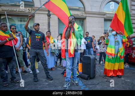 Rom, Italien. August 2023 31. 31. August 2023, Rom, Italien: Ein äthiopischer Mann der Amhara-Ethnie spricht in das Mikrofon, während Demonstranten auf beiden Seiten der Äthiopischen Flagge während der Protestdemonstration gegen die Verfolgung des Amhara-Volkes in Äthiopien schwenken, die in Rom stattfand. Nach Angaben des Hohen Kommissars der Vereinten Nationen für Menschenrechte (OHCHR) sind in der Region Amhara mindestens 183 Menschen bei Zusammenstößen ums Leben gekommen. Nach der Ausrufung des Ausnahmezustands wurden mindestens 1.000 Personen verhaftet, viele davon gehörten der ethnischen Gruppe der Amhara an und verdächtigten Unterstützung Stockfoto