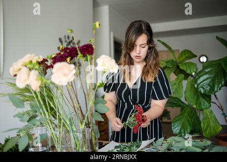 Frau, die Blumenstrauß in der Wohnung macht Stockfoto