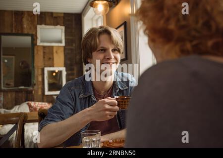 Mann, der mit rothaariger Frau am Tisch sitzt und Kaffee trinkt Stockfoto
