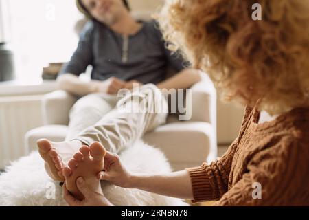 Frau, die ihrem Freund zu Hause eine Fußmassage gibt Stockfoto