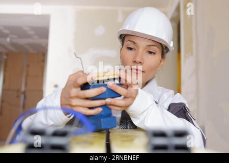 Bauarbeiterin, die Sandpapier von der Schleifmaschine wechselt Stockfoto
