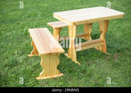 Tisch aus Holz auf grünem Gras. Tisch und Tisch. Leerer Picknickbereich. Stockfoto