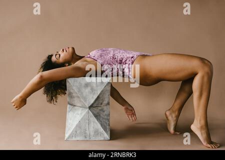 Die Tänzerin posiert auf einem Zementblock in einem pinken Trikot Stockfoto