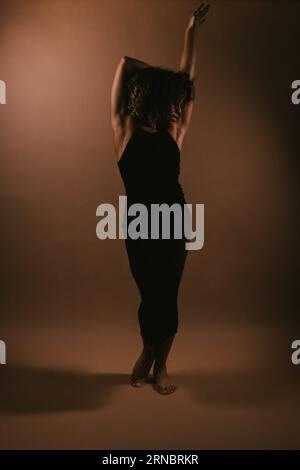 Schwarze Lockenhaartänzerin im Figurenkleid posiert im Studio Stockfoto