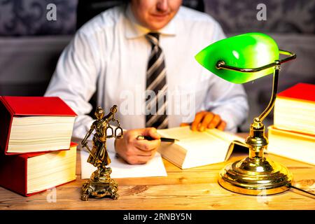 Kanzlei eines Rechtsanwalts mit Büchern und einer Statue von Lady Justice, Göttin Justitia, auf dem Schreibtisch Stockfoto