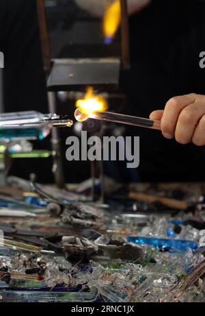 Glasarbeiter beim Formen des Glases mit einer sehr heißen Flamme in seiner Kunsthandwerkstatt in Venedig. Italien Stockfoto