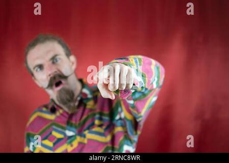 Wütender Hipster-Mann, der auf Kameraschreien und mit wütendem Ausdruck zeigt Stockfoto