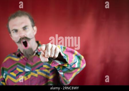 Wütender Hipster-Mann, der auf Kameraschreien und mit wütendem Ausdruck zeigt Stockfoto
