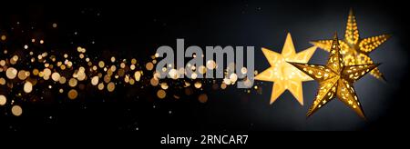 Dekorative goldene Sternlaternen für Weihnachten auf schwarzem Hintergrund mit goldenem Bokeh-Sternenstaub, extra breites Format Stockfoto