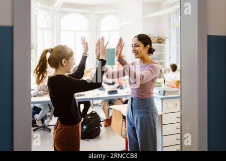 Lächelnde Lehrerin, die dem Mädchen im Klassenzimmer High-Five gibt Stockfoto