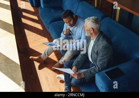 Zwei Kollegen besprechen das Projekt, bevor sie dem Teamleiter im Büro eine Präsentation zeigen Stockfoto