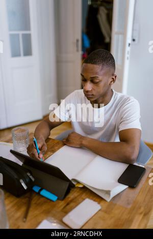Junger Mann, der zu Hause mit einem digitalen Tablet lernt Stockfoto