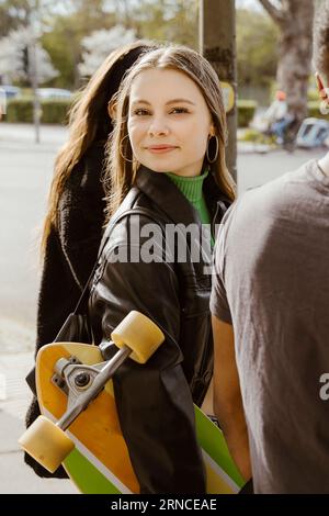 Porträt einer jungen Frau, die mit Freunden in der Stadt zurückblickt Stockfoto