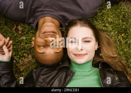 Direkt über dem Blick auf lächelnde junge Frau und Mann, die auf Gras liegen Stockfoto