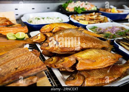 Appetitlicher frittierter Fisch auf einem Lebensmittelmarkt in Finnland. Verschiedene geräucherte Fischprodukte. Stockfoto
