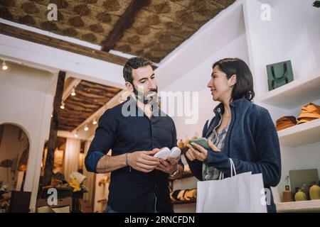 Verkäuferin und Kundin diskutieren im Bekleidungsgeschäft über Schuhe Stockfoto